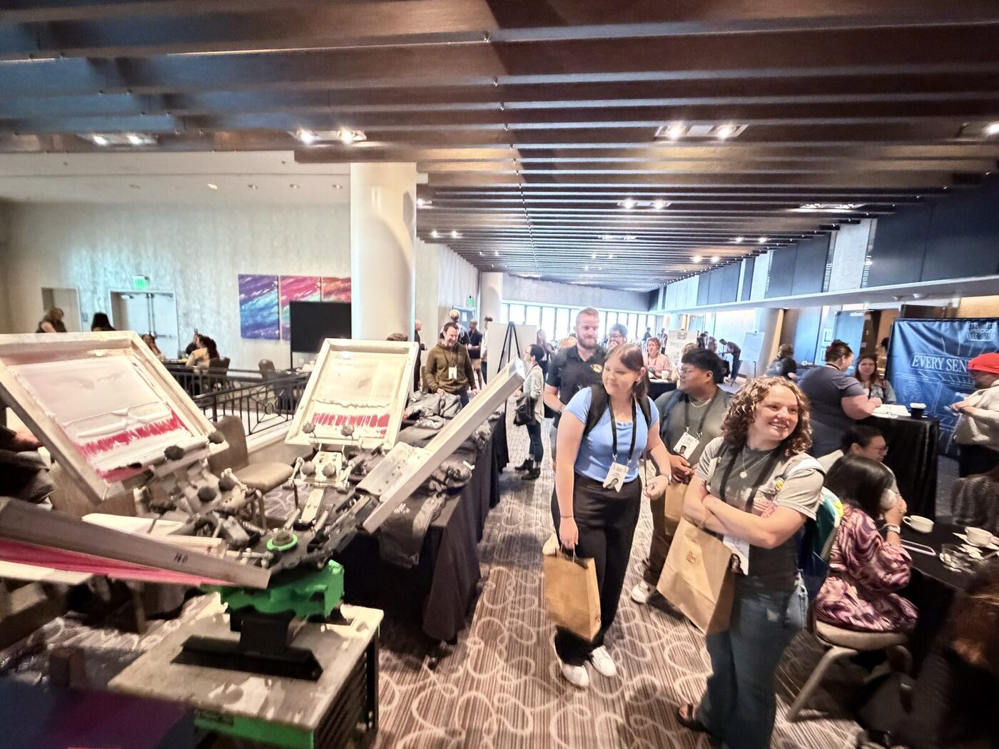 Wide view of a busy expo floor with exhibitor booths and attendees